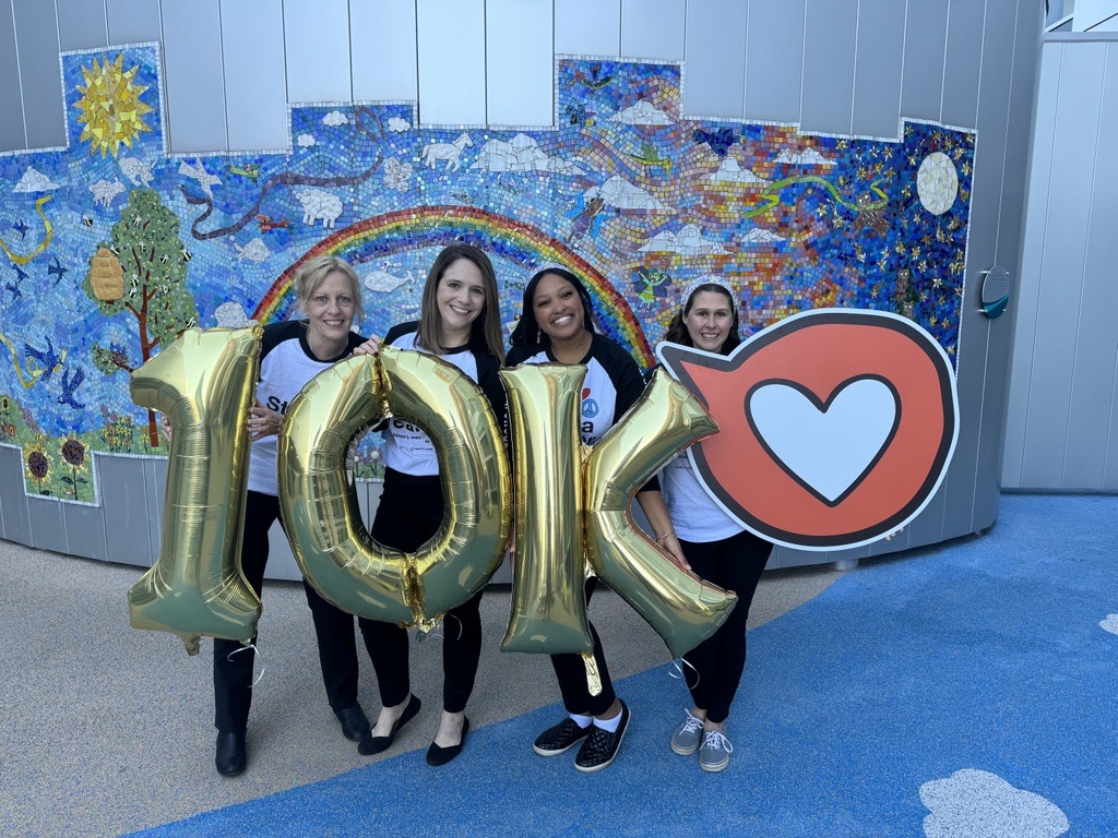 People standing with balloons and a heart sign
